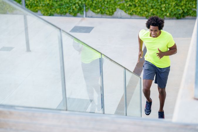Man in neon T-shirt exercising on steps outside