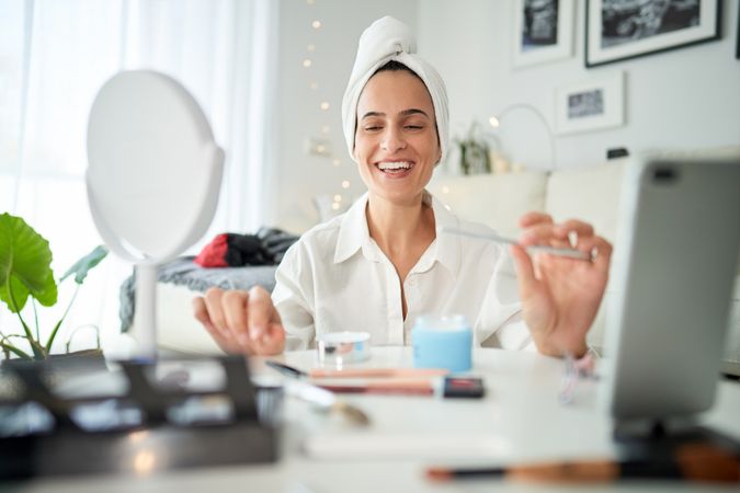 Cheerful woman recording beauty blog on smartphone
