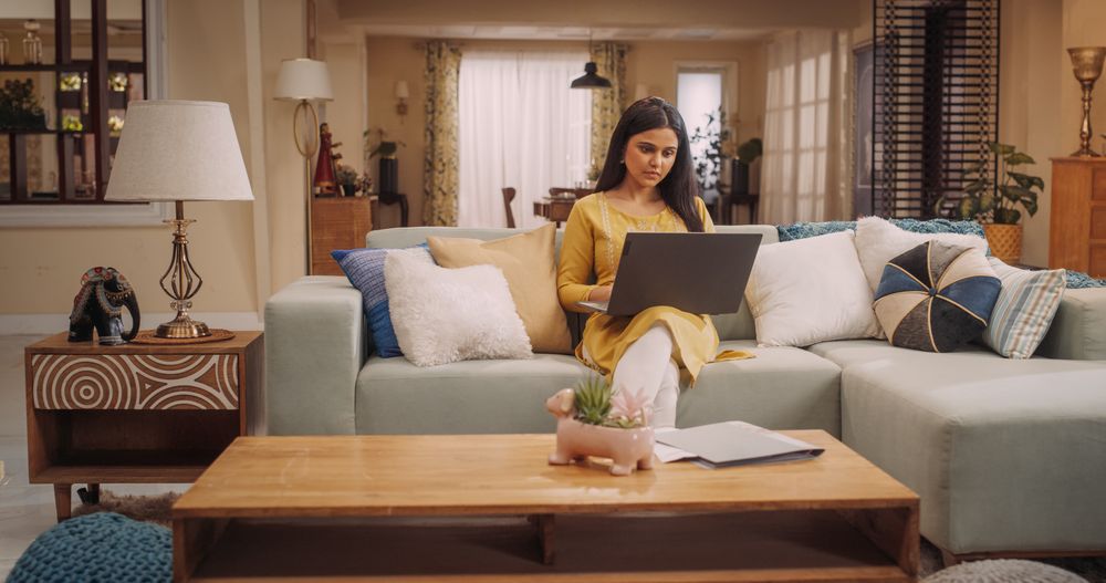 Woman Works Remotely From Home, Seated On Sofa With Laptop. Productive and Efficient at Virtual Management.