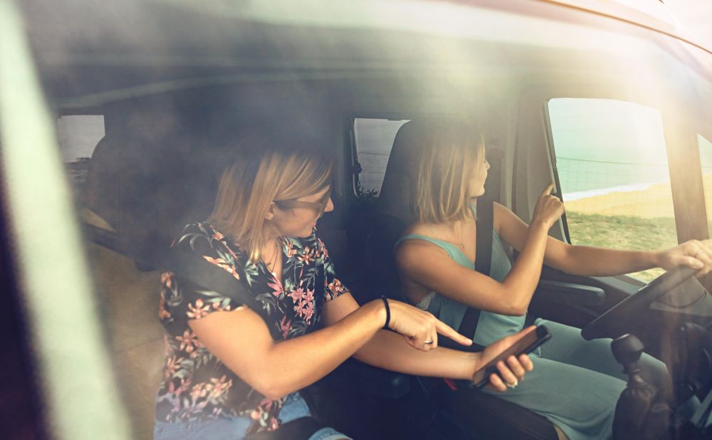 Woman enjoying view while driving a motorhome with her female friend in passenger seat