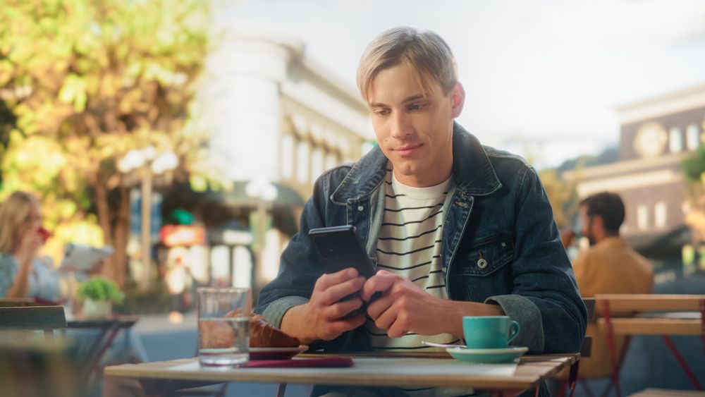 Portrait of a Young Man Typing a Message on a Smartphone Device, Replying to Friends on a Social Network Post.