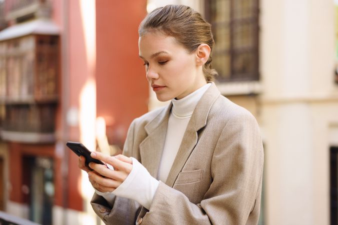 A fashionable young woman skillfully using her smartphone while outdoors in daylight