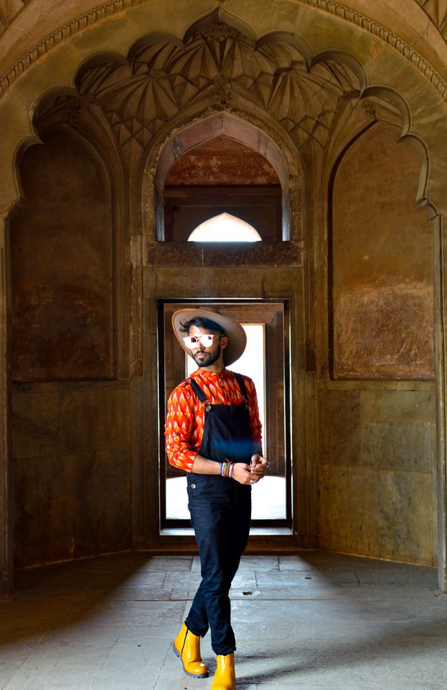 Man wearing denim dungaree and hat standing in hallway
