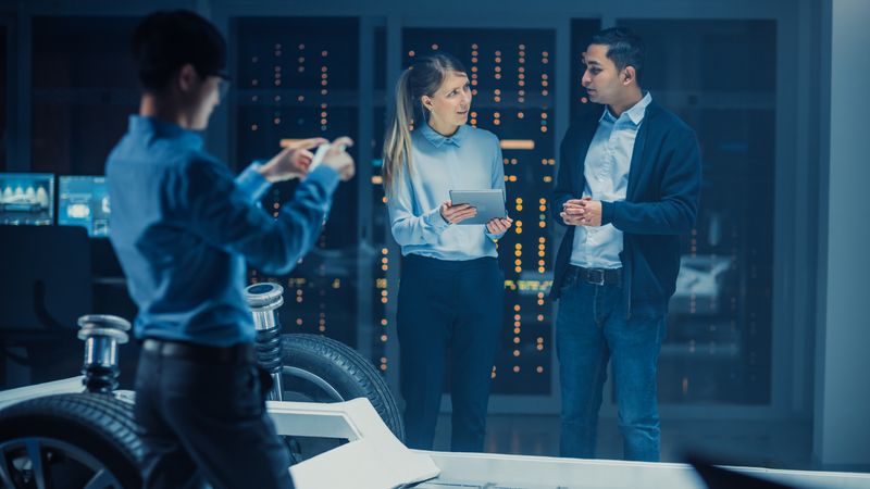 Automotive Design Engineer and Scientist with Tablet Discuss the Electric Car Chassis Prototype.