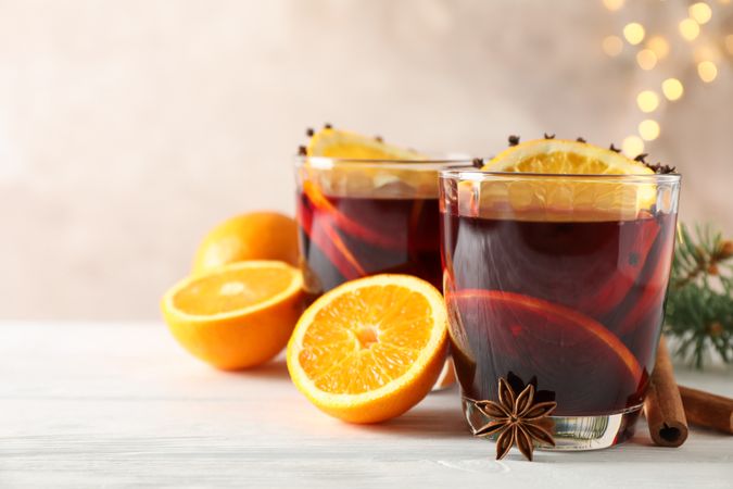 Glasses of tasty mulled wine with orange on wooden background, space for text
