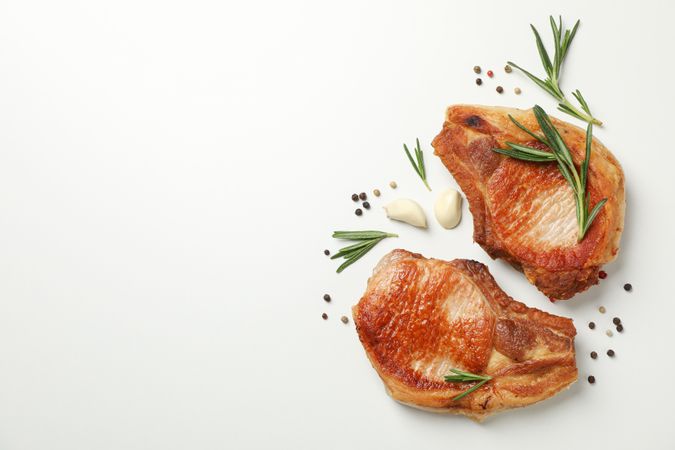 Fried steaks with spices on blank background, top view