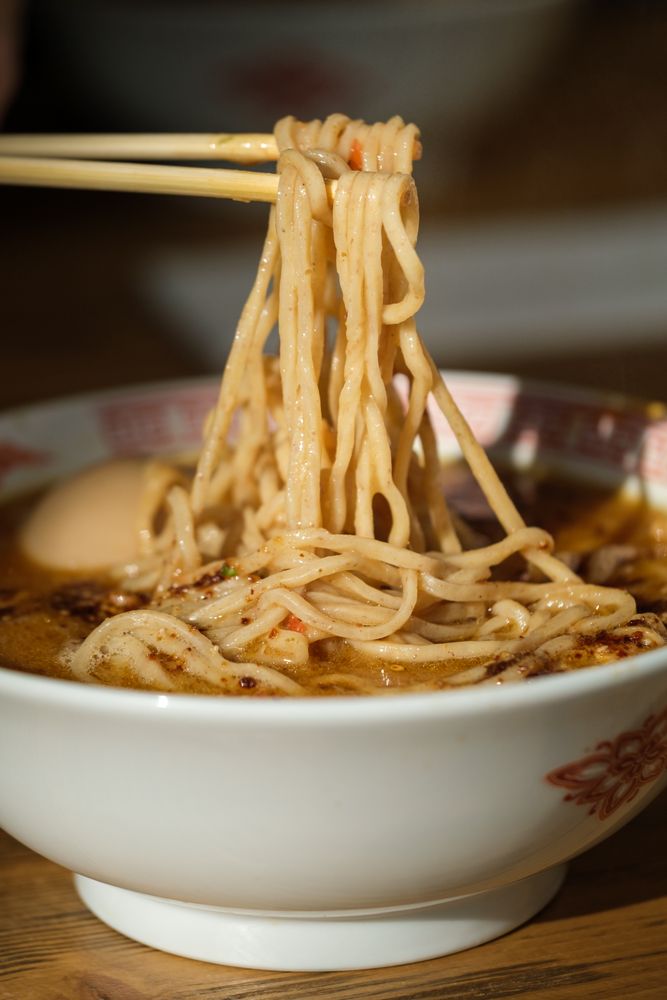 Anonymous person with chopsticks taking noodles from bowl
