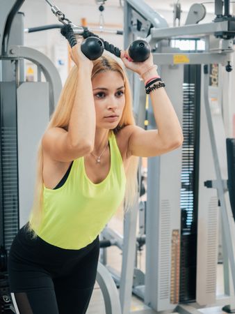 Slim woman pulling rope of exercise machine