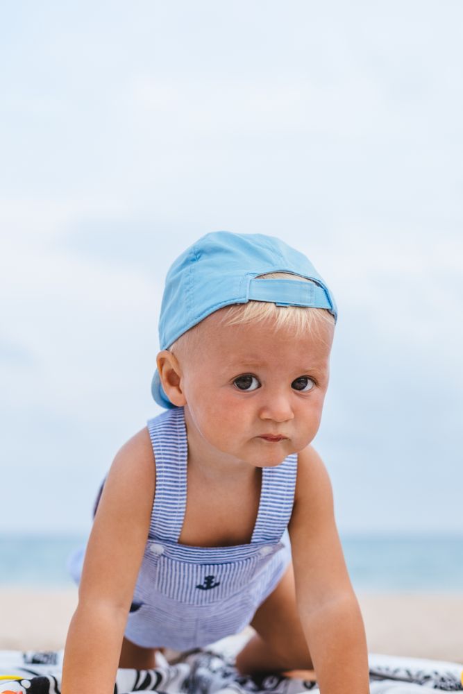 Portrait of a baby boy with his cap on the beach