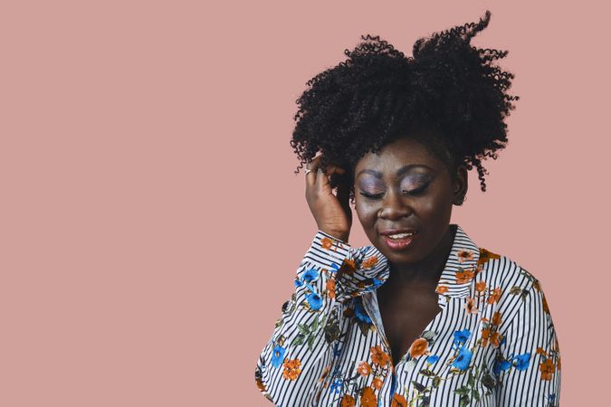 Black woman with curly hair and her eyes closed in a studio shoot