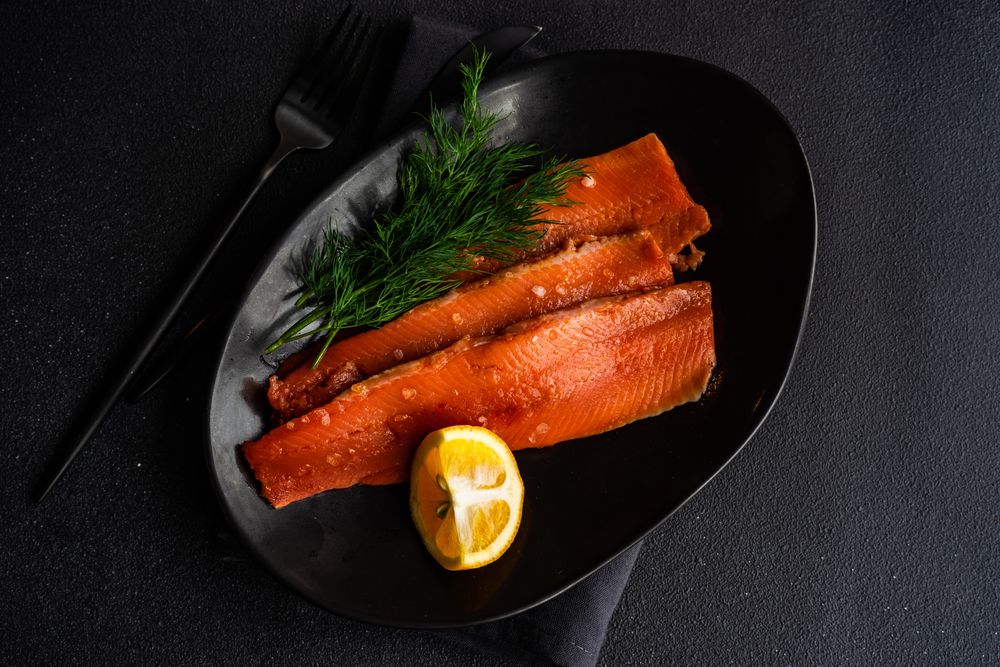 Looking down at raw herring fish with dill and lemon served on plate