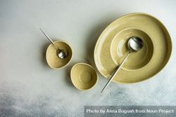 Rustic table setting with three yellow bowls and spoons 4djxD0