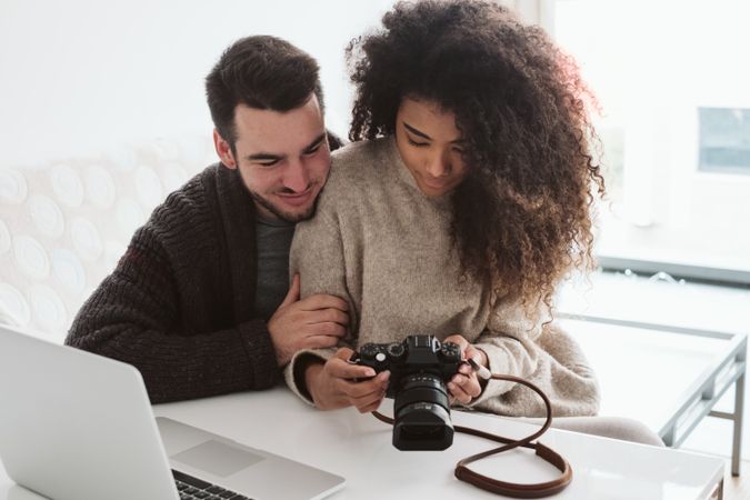 Multiracial couple looking at photo camera at home