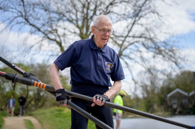 Grey haired man with oars for row boat