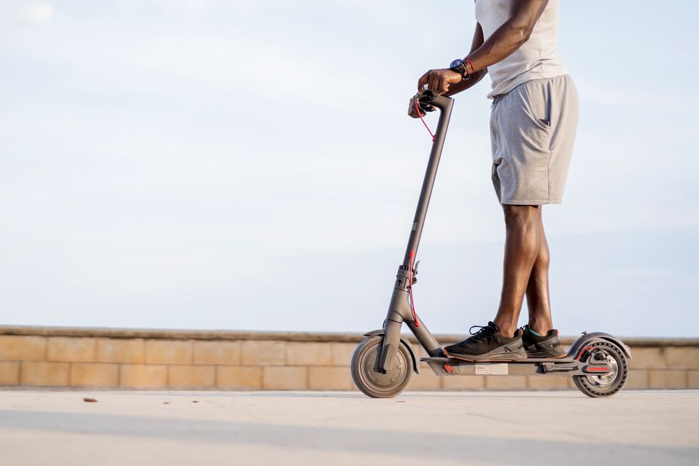 Black man riding scooter in street
