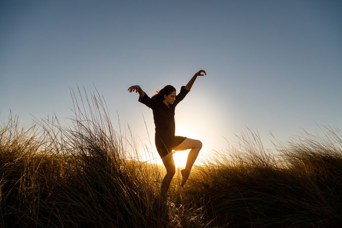 Woman posing between field at sunset