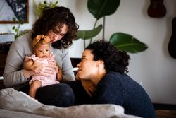 Happy married couple relaxing with baby in living room