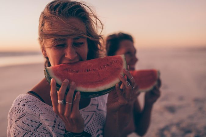 Young woman eating a watermelon slice at the beach