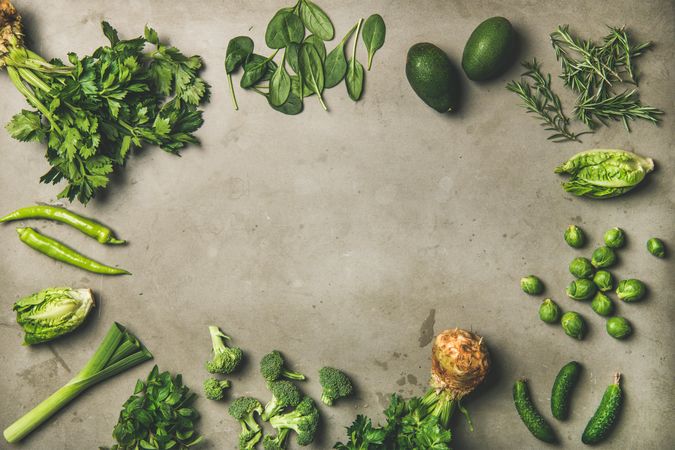 Arrangement of fresh green garden vegetables on concrete surface, copy space