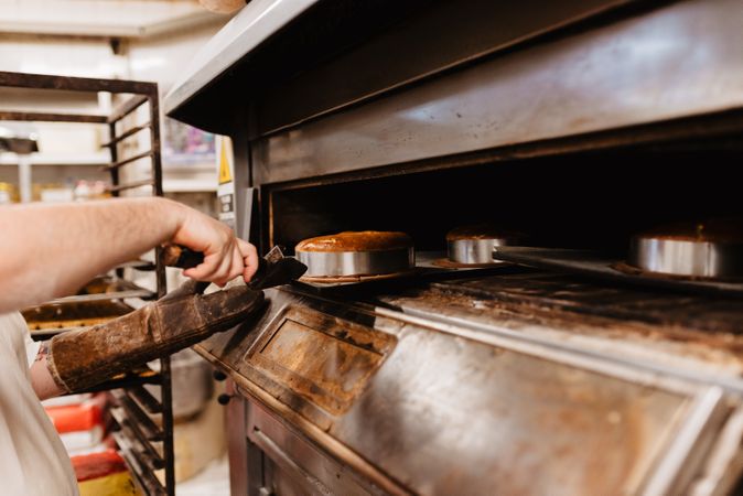 Bald baker checking pastry inside oven