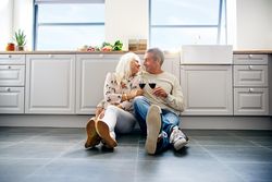 Mature couple looking at each other affectionately on the kitchen floor