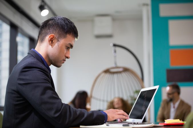 Man working in colorful office with colleagues in the background