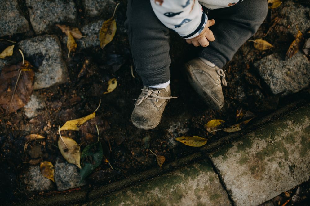 Cropped shot of toddler’s shoes sitting outside