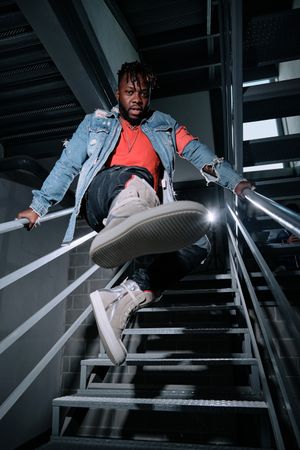 Stylish Black man holding on railing on stairs