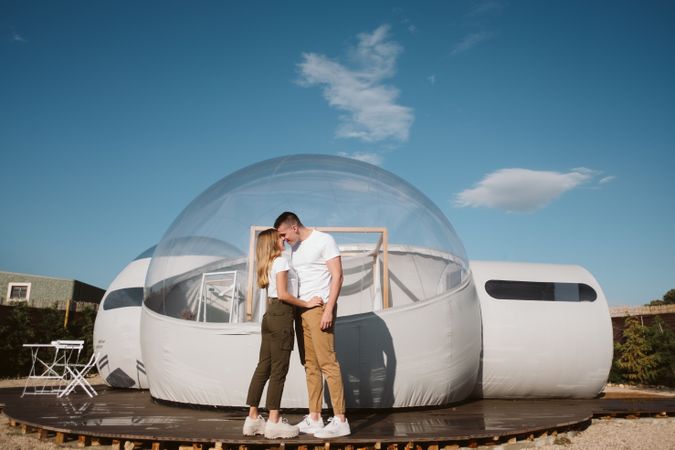 Affectionate couple kissing near bubble hotel