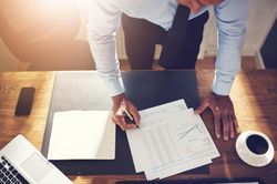 Overhead shot of man in business attire signing documents at his desk