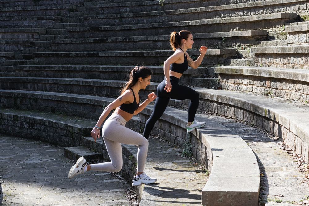 Slim women in sportswear exercising on stairs before doing yoga