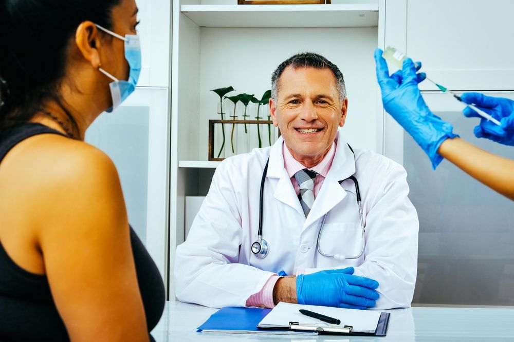 Medical assistant preparing injection for patient in smiling doctor’s office