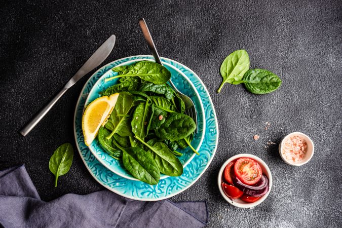 Looking down at healthy spinach salad with lemon slice