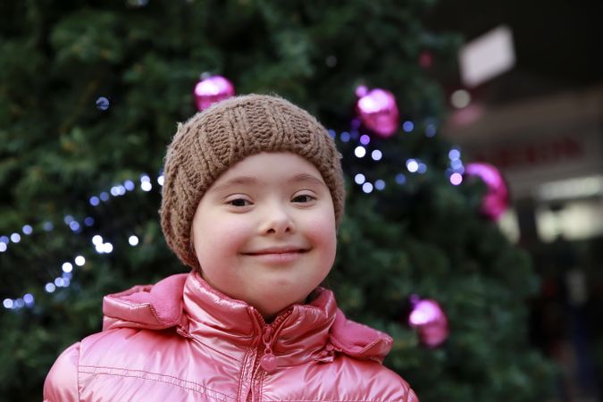 Cheerful young child standing near a holiday decorated tree