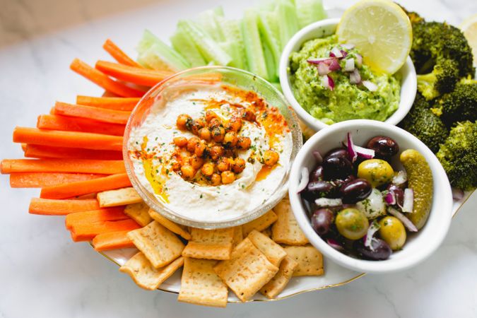 Tasty hummus and sauces decorated with bright cut vegetables on table