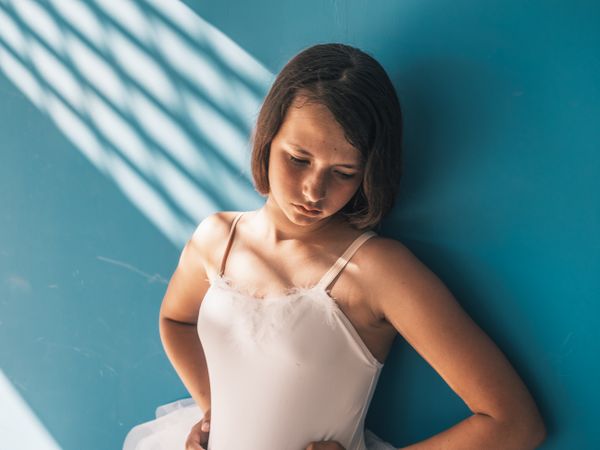 Ballerina standing with sad face near wall