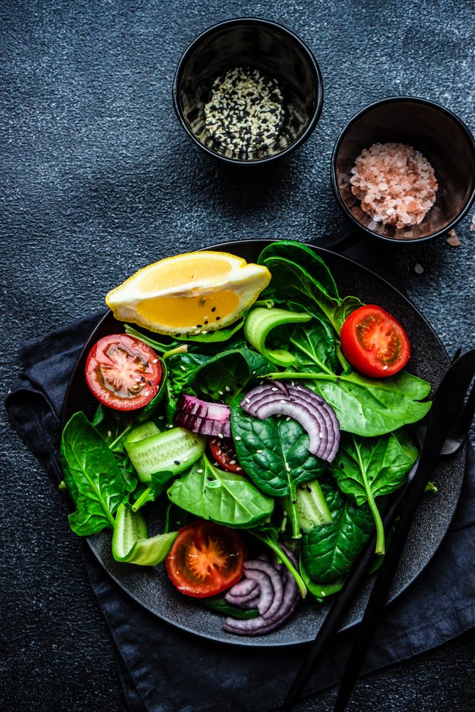 Top view of spinach salad with cherry tomatoes, served with sesame seeds