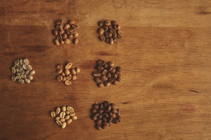 Different grades of roasting beans on a weathered driftwood background