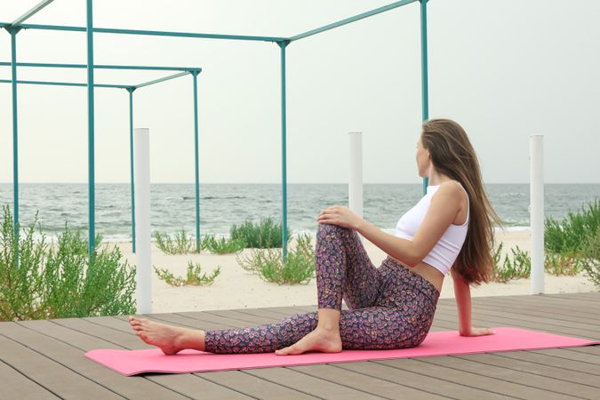 Woman on yoga mat on wooden floor outdoors