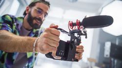 Focused Young Male Filmmaker With Beard, Adjusting Camera Equipment In Studio, Capturing Content For Advertising Project, Showcasing Diversity And Creativity In Modern Cinematography.