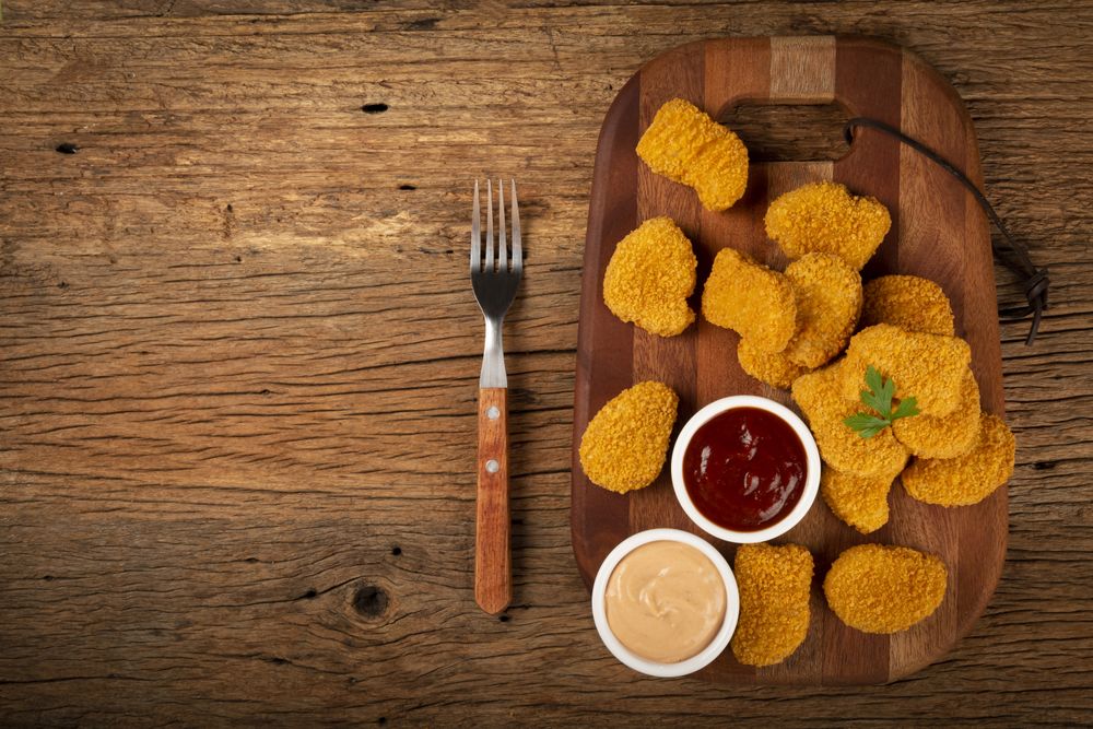 Fried chicken nuggets with ketchp and rose sauce.