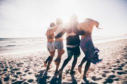 Group of friends people walking along with the beach