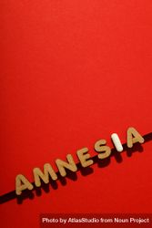 Cork letters of the word “Amnesia” with pill along bottom of red background, vertical composition 4O6KR5
