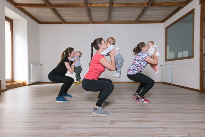 Mothers lifting babies in gym