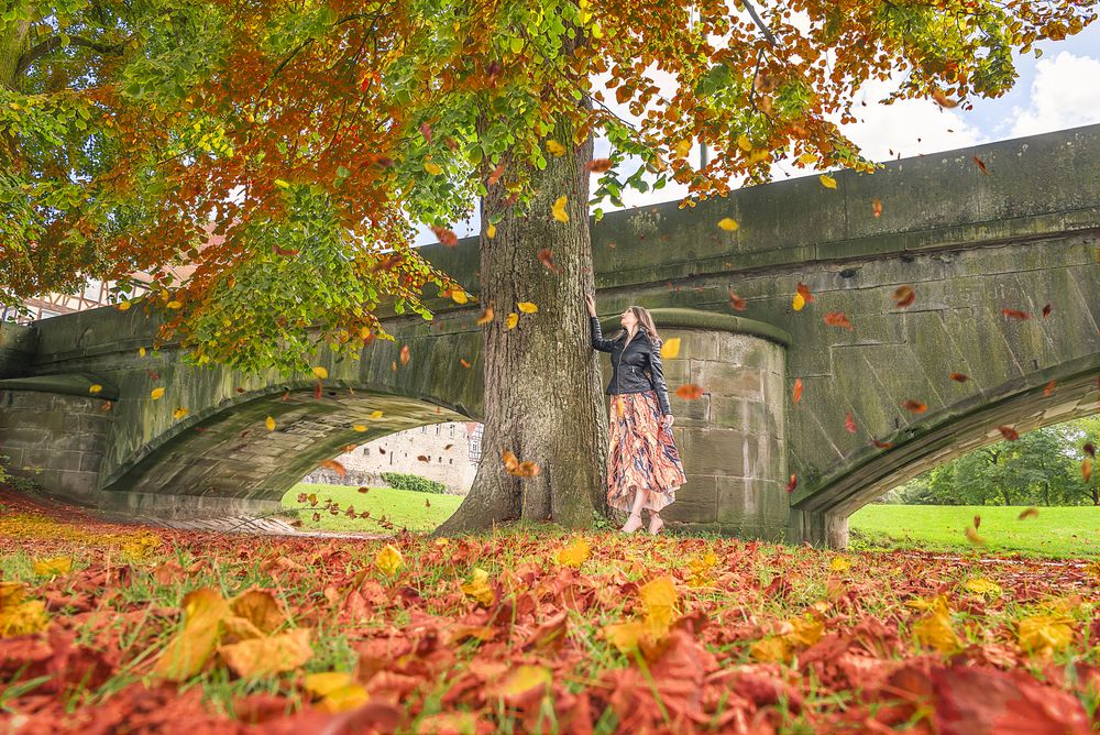Woman under a tree with falling leaves