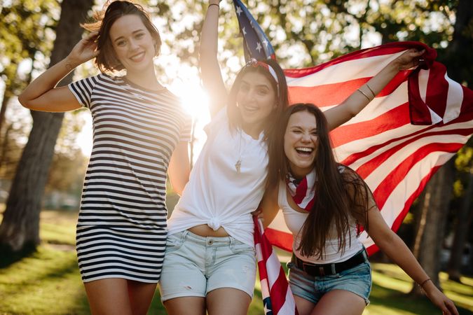 Smiling women at park with USA flag on a sunny day