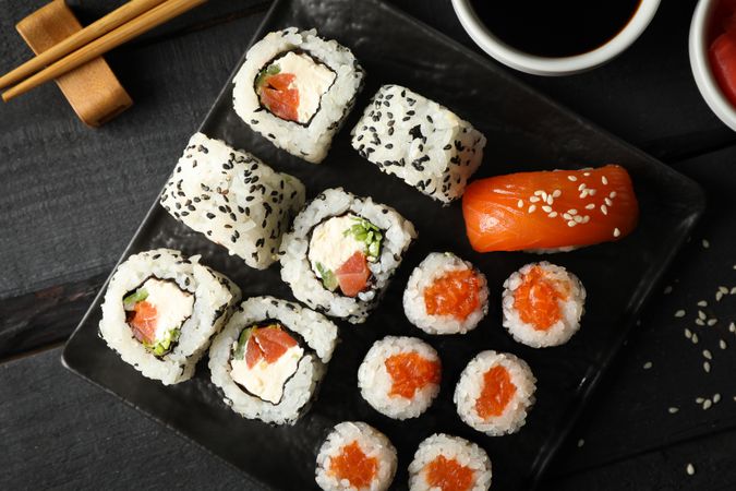 Tray with delicious sushi rolls on wooden background, top view. Japanese food
