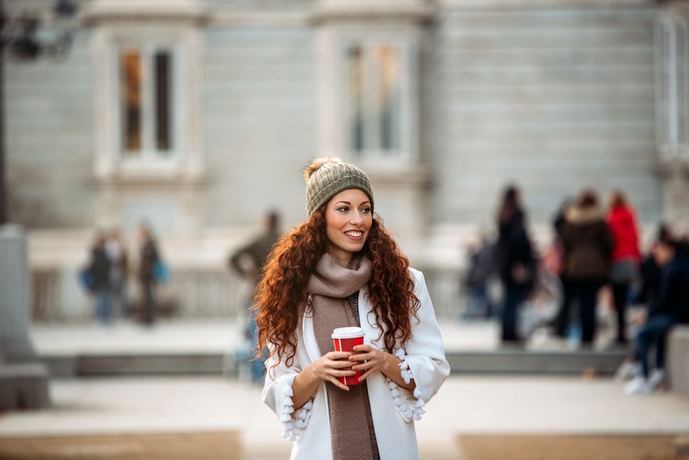 Woman drinking coffee wandering in the streets of Madrid on winter