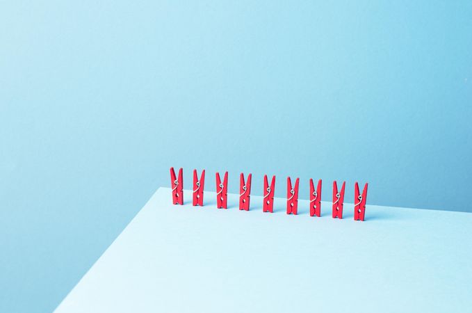 Red clothes pins on light blue background