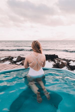 Woman sitting in pool near stones